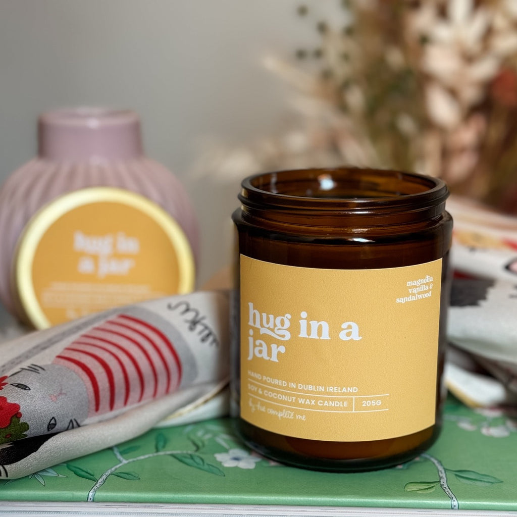hug in a jar magnolia, vanilla and sandalwood scented best selling candle hand poured in Dublin, Ireland. In an amber jar with matching gold lid